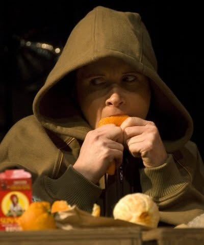 Christine Samson in a hooded sweatshirt, holding an orange at a table